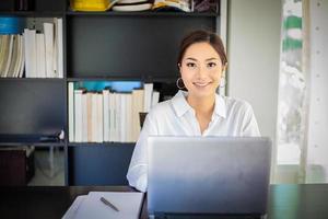 donne d'affari asiatiche che usano il taccuino e sorridono felici di lavorare foto