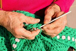 un anziano donna è maglieria un' verde uncinetto Borsa foto