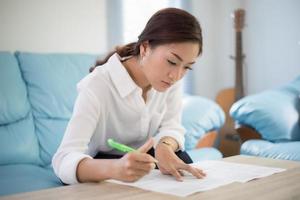 belle donne d'affari asiatiche che scrivono i dati che controllano il documento e sorridono felici per il lavoro foto