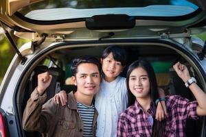 bambina felice con la famiglia asiatica seduta in macchina per godersi il viaggio e le vacanze estive in camper foto