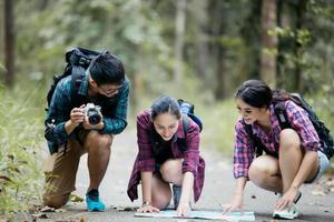 gruppo asiatico di giovani che fanno escursioni con gli amici zaini camminano insieme e guardano la mappa e prendono la macchina fotografica lungo la strada e sembrano felici, tempo di relax durante il concetto di vacanza viaggio foto