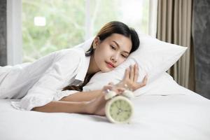 donna asiatica felice di svegliarsi e spegnere la sveglia con una buona giornata