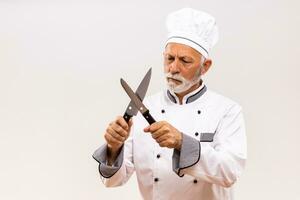 Immagine di arrabbiato capocuoco affila coltelli su grigio sfondo. foto