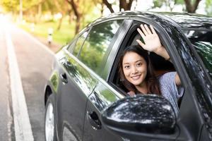 bella donna asiatica che sorride e si diverte. Guidare un'auto su strada per viaggiare? foto