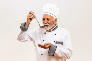 ritratto di soddisfare anziano capocuoco degustazione la minestra. foto