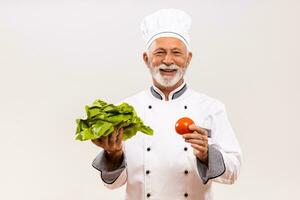 ritratto di anziano capocuoco Tenere verdure su grigio sfondo. foto