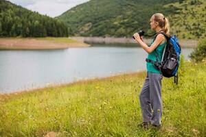 donna escursionista utilizzando binocolo mentre la spesa tempo nel il bellissimo natura. foto