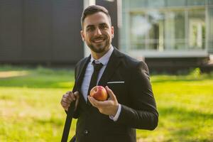 elegante uomo d'affari è mangiare Mela a il parco.tonico foto. foto