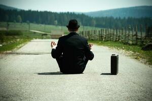 bandire nel un' completo da uomo seduta su il strada con un' valigia e Meditare foto