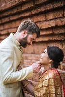 la sposa asiatica e lo sposo caucasico hanno un momento romantico con il vestito thailandese