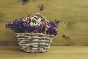 Immagine di bellissimo secco fiori nel cestino su di legno sfondo. foto