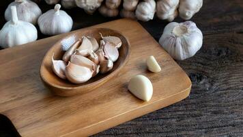 biologico crudo aglio lampadina, aglio Chiodi di garofano su di legno tazza, di legno taglio asse, di legno tavolo e aglio Chiodi di garofano di cibo ingredienti foto