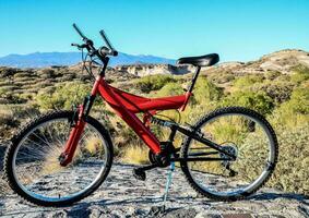 un' rosso montagna bicicletta seduta su superiore di un' roccia foto