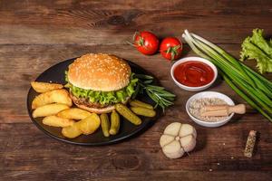 gustoso hamburger fatto in casa alla griglia con manzo, pomodoro, formaggio, cetriolo e lattuga foto