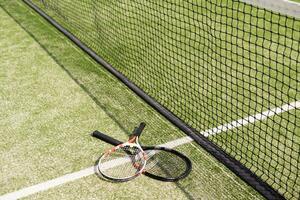 una racchetta da tennis e una pallina da tennis nuova su un campo da tennis dipinto di fresco foto