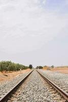 un' treno traccia nel il deserto con un' nuvoloso blu cielo foto