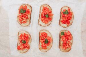 delizioso Bruschetta, tostato pane con pomodori su bianca carta, superiore Visualizza foto