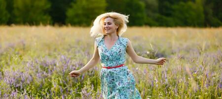 all'aperto ritratto di un' bellissimo mezzo anziano bionda donna. attraente sexy ragazza nel un' campo con fiori foto