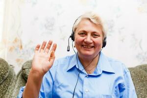 poco carino ragazza e sua nonna siamo la spesa tempo insieme a casa. avendo divertimento, abbracciare e sorridente mentre seduta su divano. foto