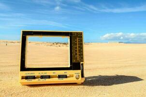 un' giallo rotto televisione su il sabbia foto