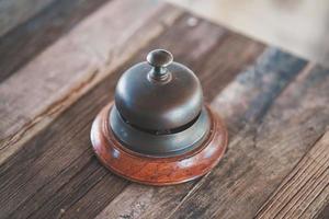 campanello d'epoca della reception dell'hotel sul tavolo di legno. vecchio stile retrò foto