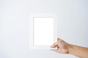 una mano di un uomo tiene una cornice bianca vuota su sfondo bianco foto