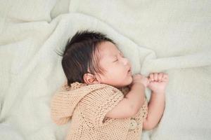 adorabile neonato che dorme pacificamente su una coperta bianca foto