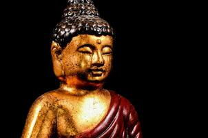 un' statua di un' Budda seduta su un' nero sfondo foto