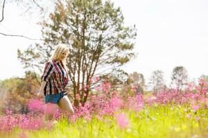 contento avventuriero femmina sta su il verde montagna pendenza tra fioritura rosa rododendri e guardare in il distanza. epico viaggio nel il montagne. largo angolo. foto