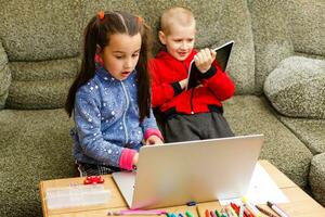 Due bellissimo carino contento sorridente figli, un' ragazzo e un' ragazza, uso il computer portatile per distanza apprendimento o intrattenimento. foto