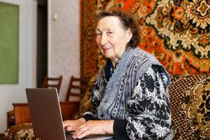 tecnologia, vecchio età e persone concetto - contento anziano donna avendo video chiamata a casa nel sera foto