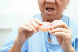 asiatico anziano donna paziente indossare denti dentiera in sua bocca per masticare cibo. foto