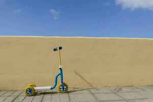 un' piccolo blu scooter contro un' giallo parete foto