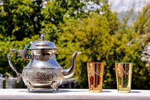 un' argento tè pentola e Due oro tazze su un' tavolo foto