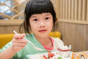 carino poco asiatico bambino ragazza mangiare cibo foto