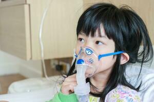malato poco asiatico ragazza inalazione con nebulizzatore per respiratorio trattamento foto