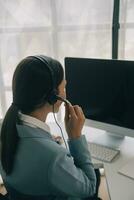 bellissimo femmina chiamata centro operatore Lavorando su computer nel ufficio foto