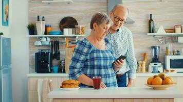 più vecchio coppia durante video Chiacchierare con famiglia utilizzando smartphone nel cucina. nonni in linea conversazione. anziano persone con moderno tecnologia nel la pensione età utilizzando mobile applicazioni foto