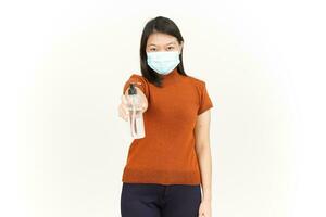 indossare medico maschera e Tenere mano disinfettante di bellissimo asiatico donna isolato su bianca foto