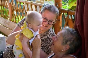 la nonna per coccolarsi dalla gioia al neonato in sottofondo con sua madre foto