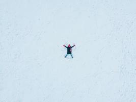 donna felice che fa l'angelo della neve foto