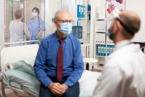 infermiera nel ospedale corridoio discutere con portatori di handicap anziano donna con a piedi telaio. medico professionista nel il corso di privato moderno clinica appuntamento durante coronavirus pandemia. foto