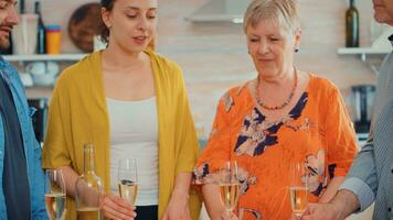 contento famiglia festeggiare a casa applauso un' bicchiere di Champagne. persone di Due generazioni parlando, seduta in giro il tavolo tostatura e festeggiare un evento potabile un' bicchiere di bianca vino. foto