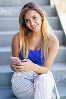 ragazza che usa uno smartphone touchscreen indossando abiti casual foto