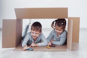due ragazzini un ragazzo e una ragazza che giocano a macchinine in scatole di cartone. foto di concetto. i bambini si divertono. foto di concetto. i bambini si divertono