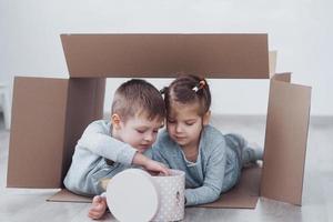 due bambini piccoli ragazzo e ragazza che giocano in scatole di cartone. foto di concetto. i bambini si divertono