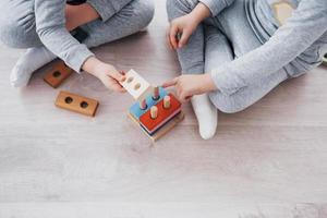 i bambini giocano con un designer di giocattoli sul pavimento della stanza dei bambini. due bambini che giocano con blocchi colorati. giochi educativi per la scuola materna foto