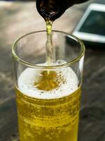 scrosciante birra in bicchiere su di legno tavolo foto