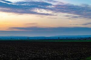 un' campo a tramonto con nuvole foto