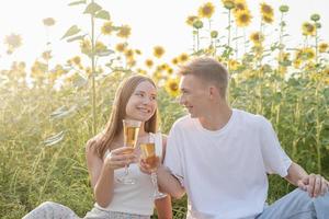 giovane coppia che fa picnic sul campo di girasoli al tramonto foto